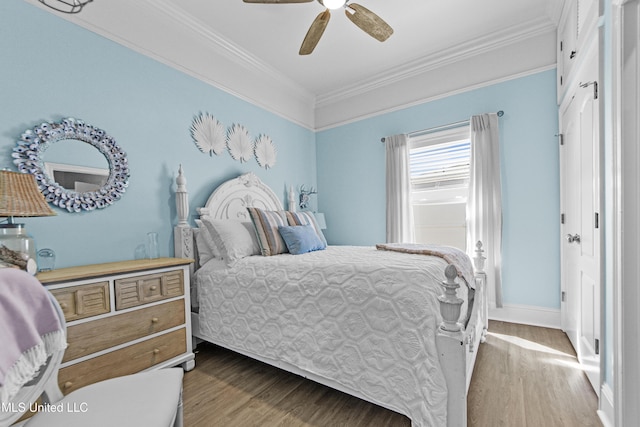 bedroom featuring baseboards, wood finished floors, a ceiling fan, and crown molding