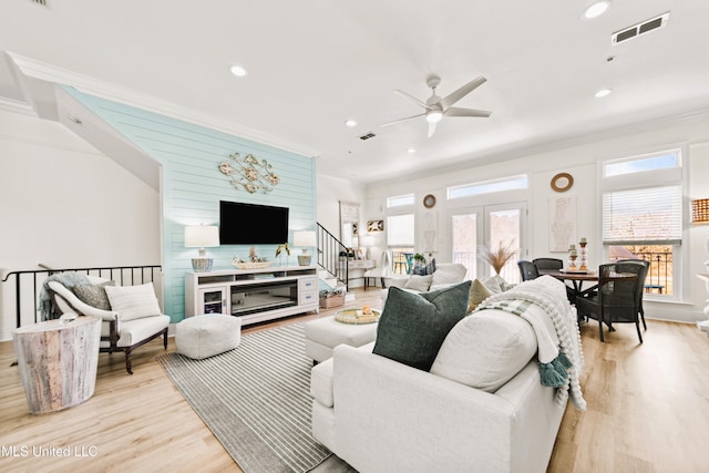 living area featuring light wood-style floors, visible vents, crown molding, and recessed lighting