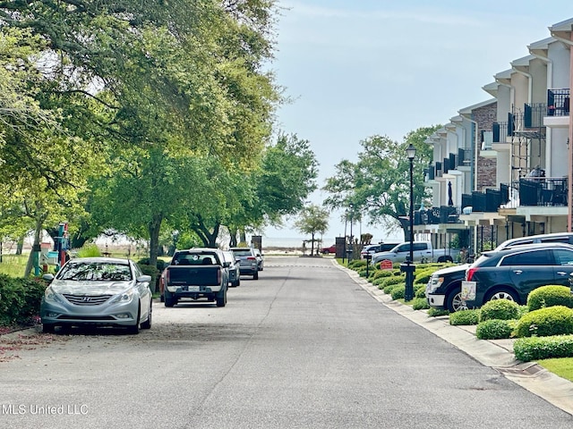 view of asphalt street featuring street lights and curbs
