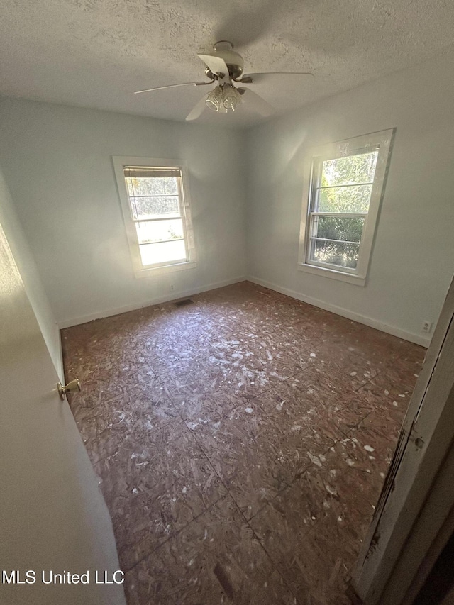 empty room with plenty of natural light, ceiling fan, and a textured ceiling