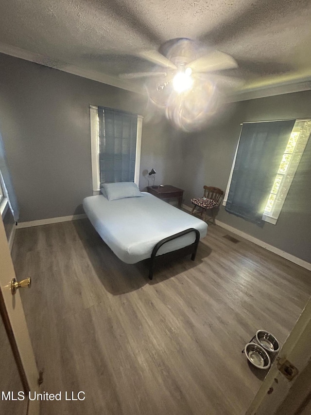 bedroom featuring ceiling fan, wood-type flooring, and a textured ceiling