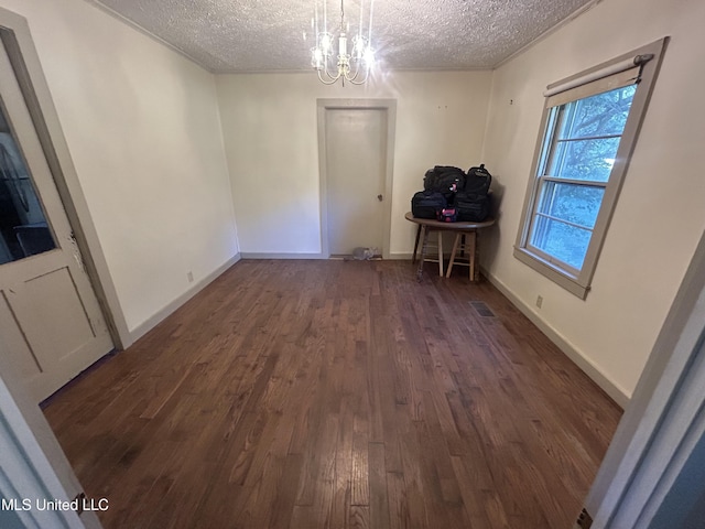 unfurnished dining area with a textured ceiling, dark hardwood / wood-style floors, and a notable chandelier