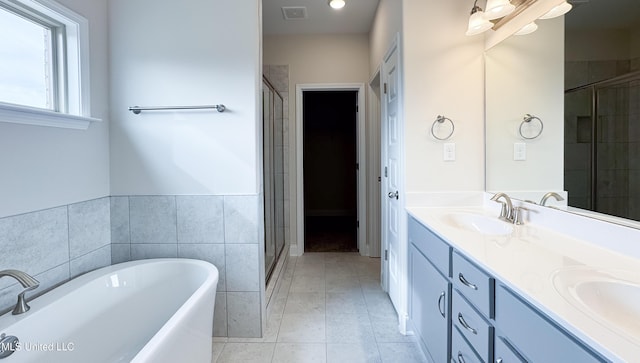 bathroom with separate shower and tub, vanity, tile walls, and tile patterned floors