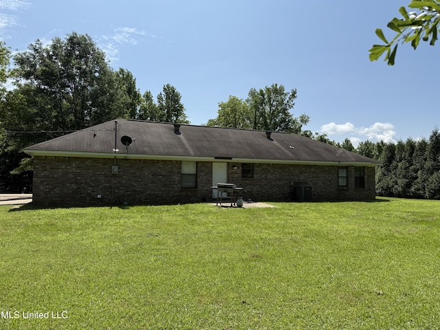 rear view of property with a lawn, brick siding, and central AC unit