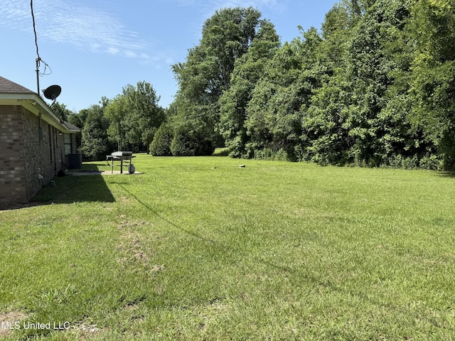 view of green lawn with central air condition unit