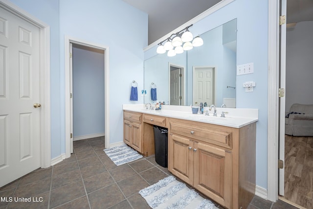 bathroom with tile patterned flooring, double vanity, baseboards, and a sink