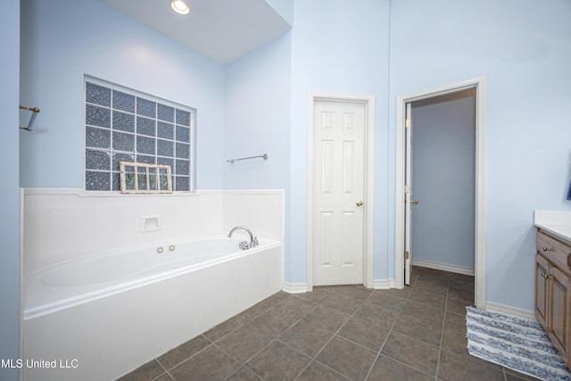 bathroom featuring recessed lighting, tile patterned flooring, baseboards, a bath, and vanity