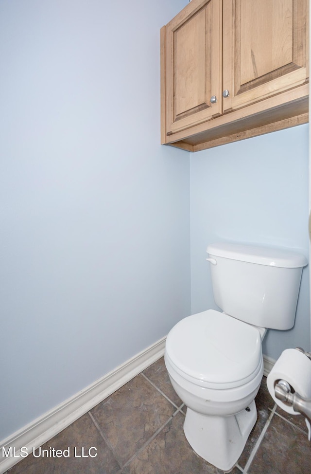 bathroom featuring toilet, stone finish flooring, and baseboards