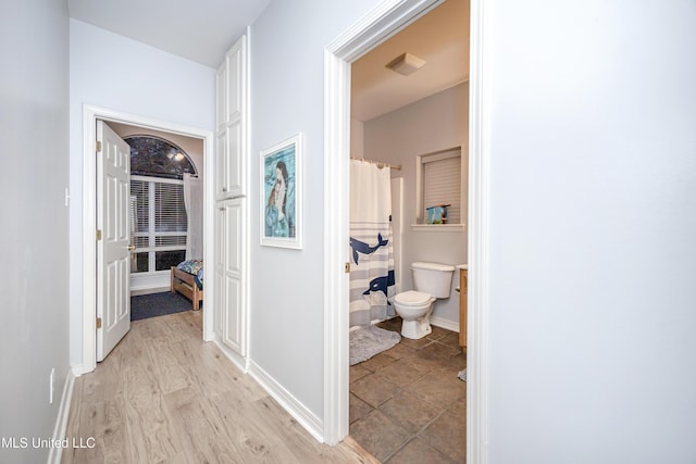 corridor featuring light wood-style flooring and baseboards