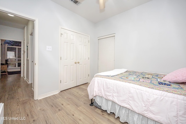 bedroom featuring light wood finished floors, visible vents, baseboards, a closet, and a ceiling fan