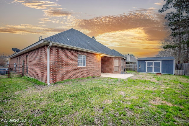 back of house with brick siding, a patio area, an outbuilding, and a fenced backyard