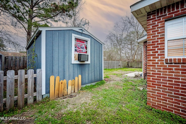 outdoor structure at dusk featuring an outdoor structure, a storage unit, and fence