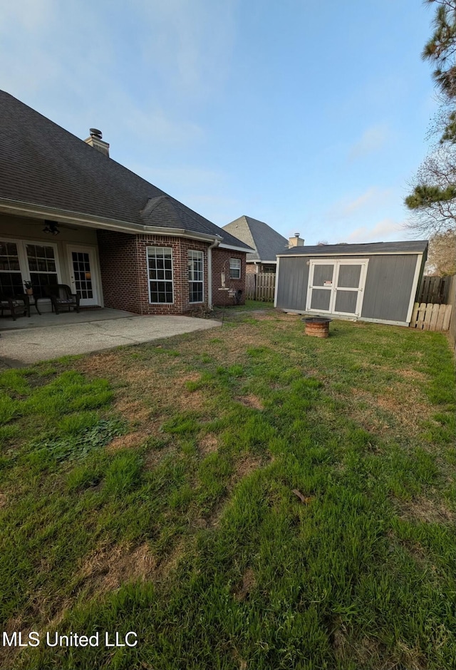 view of yard with a patio area, fence private yard, an outbuilding, and a ceiling fan