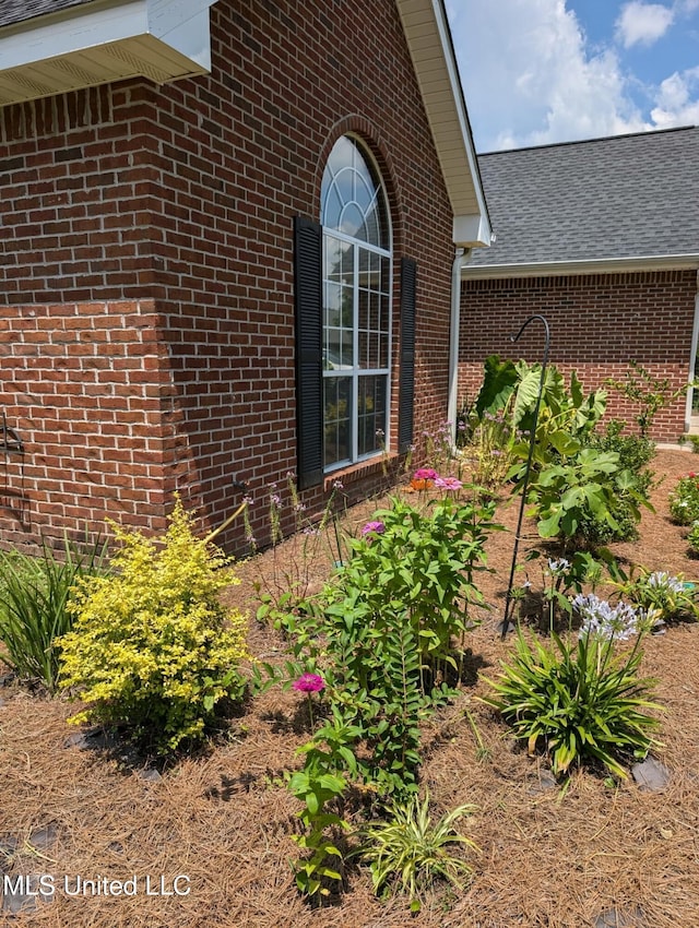 view of property exterior featuring brick siding and roof with shingles