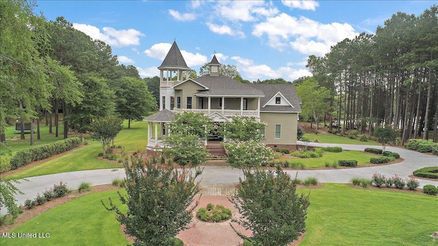 victorian-style house featuring a balcony, covered porch, and a front yard