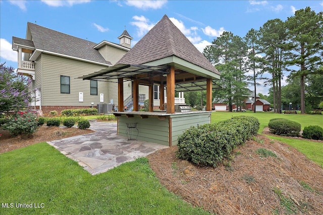 rear view of property featuring a patio, a lawn, central air condition unit, and a bar