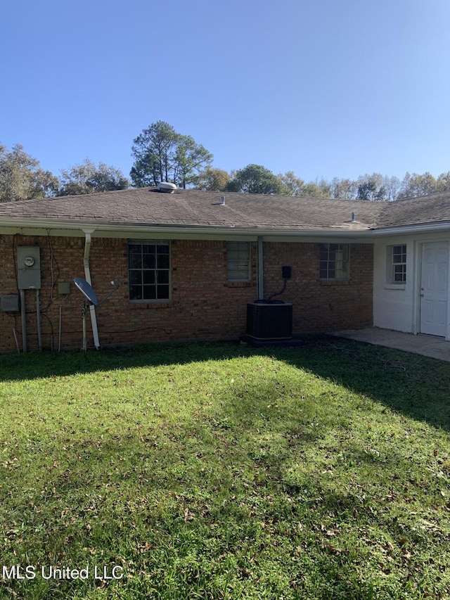 back of house with central AC and a lawn