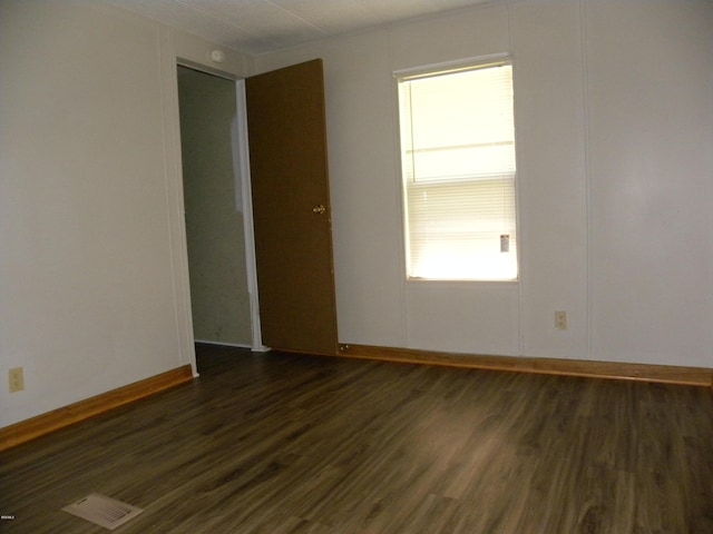 empty room featuring baseboards and dark wood finished floors