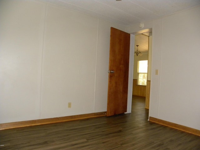 spare room with baseboards and dark wood-style flooring