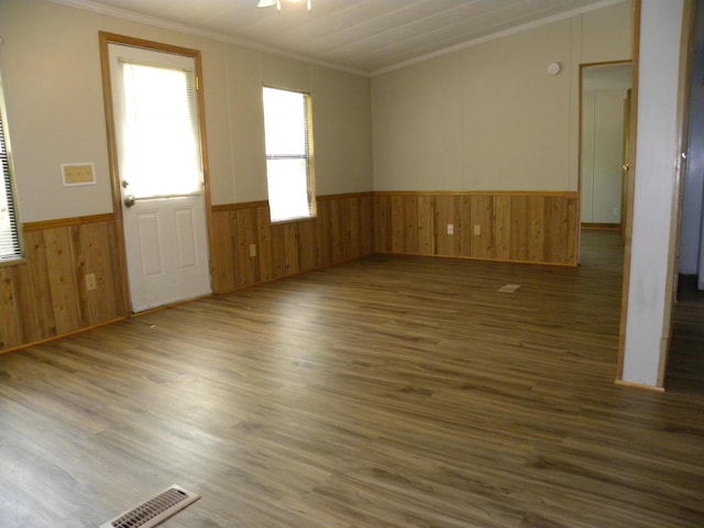 spare room with crown molding, wood walls, a wainscoted wall, and wood finished floors