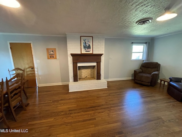 living room with crown molding, dark hardwood / wood-style floors, a textured ceiling, and a brick fireplace