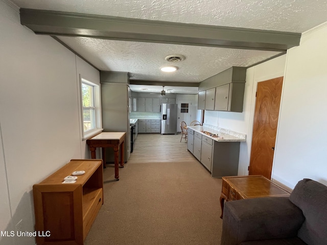 kitchen featuring crown molding, light wood-type flooring, a textured ceiling, stainless steel fridge, and beam ceiling