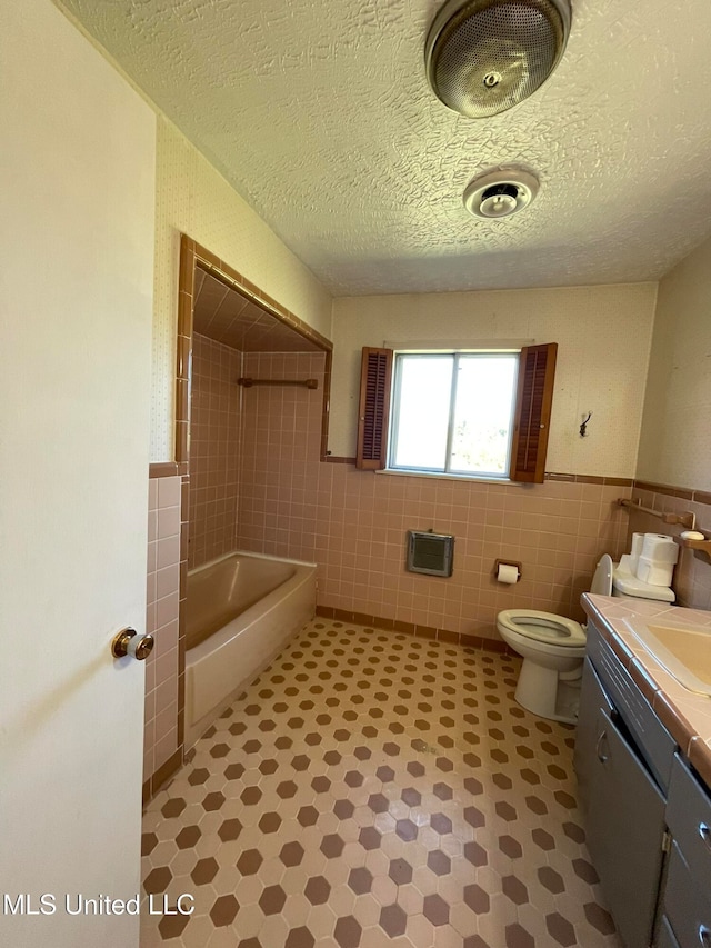 full bathroom featuring vanity, tile walls, a textured ceiling, and toilet