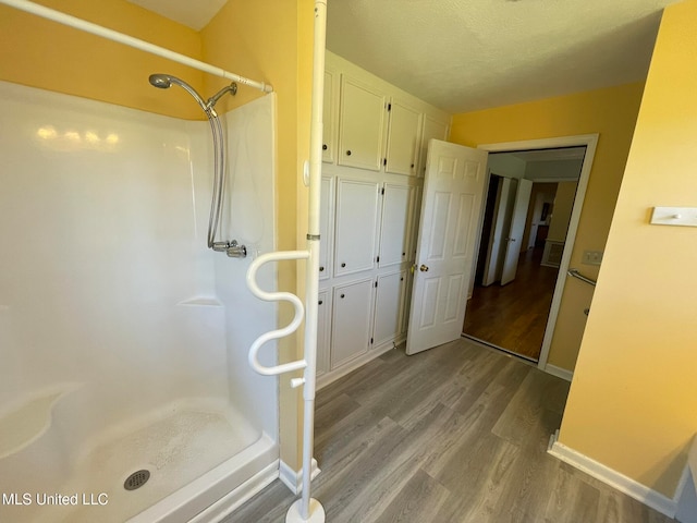 bathroom featuring hardwood / wood-style floors, a shower, and a textured ceiling