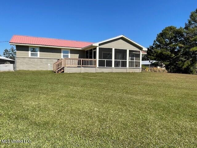 rear view of property with a sunroom and a lawn