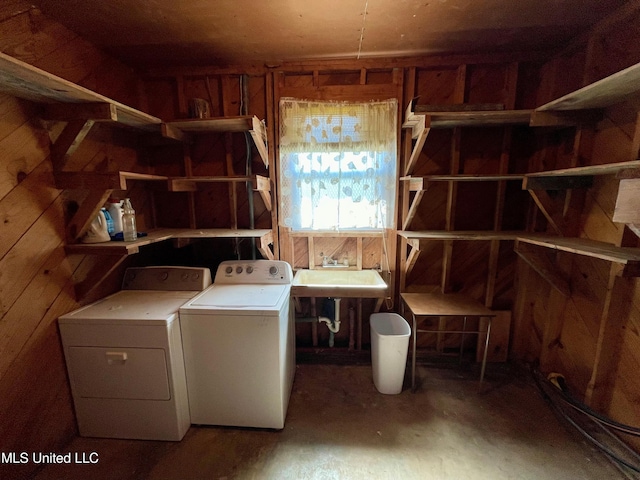 washroom with wood walls, sink, and washing machine and clothes dryer