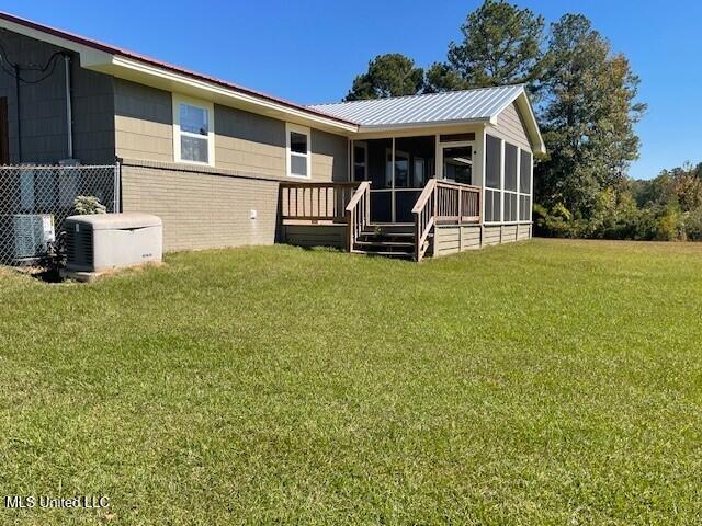 back of property featuring a deck, a lawn, and a sunroom