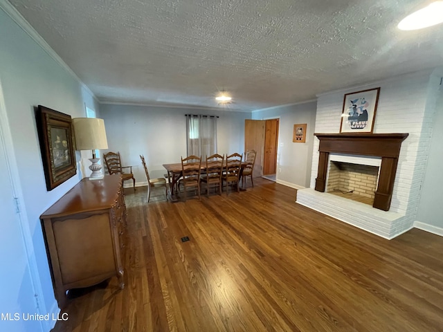 living room with a textured ceiling, ornamental molding, a brick fireplace, and hardwood / wood-style floors