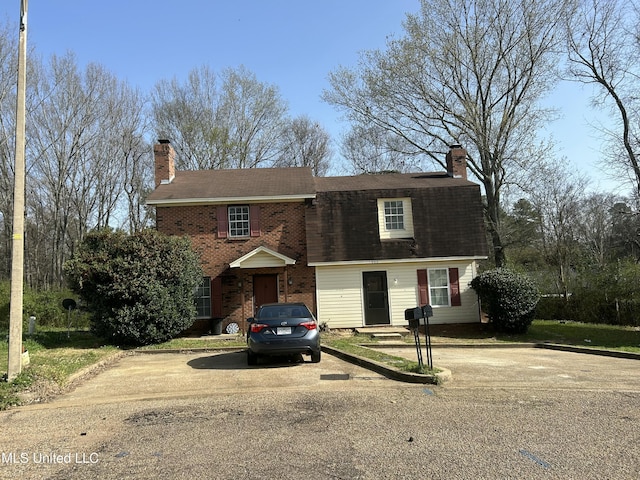 view of front of home featuring brick siding and a chimney