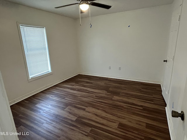 spare room with dark wood finished floors, a ceiling fan, and baseboards