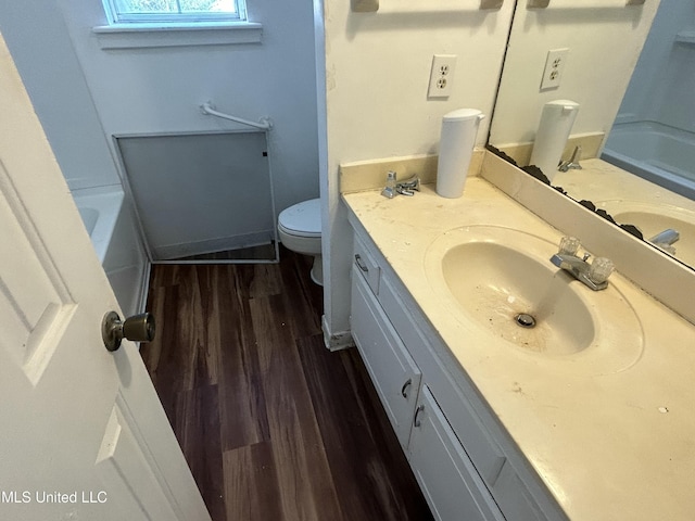full bathroom with a tub, toilet, wood finished floors, and vanity