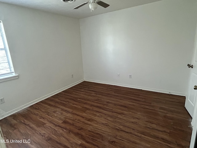 empty room featuring baseboards, dark wood finished floors, and a ceiling fan