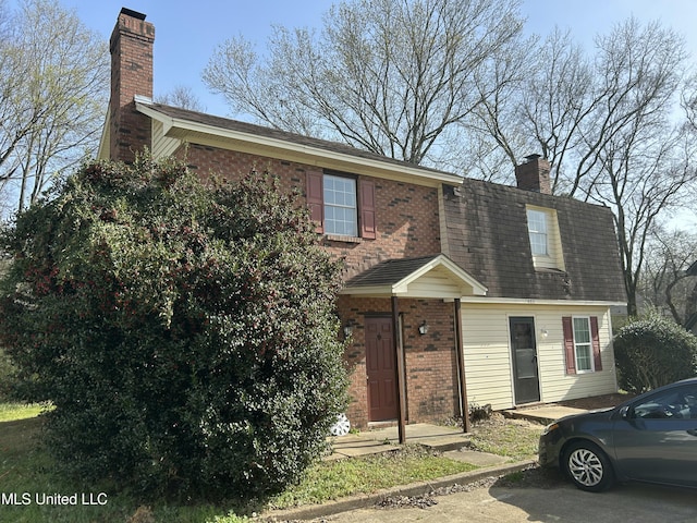 view of front of house with brick siding and a chimney