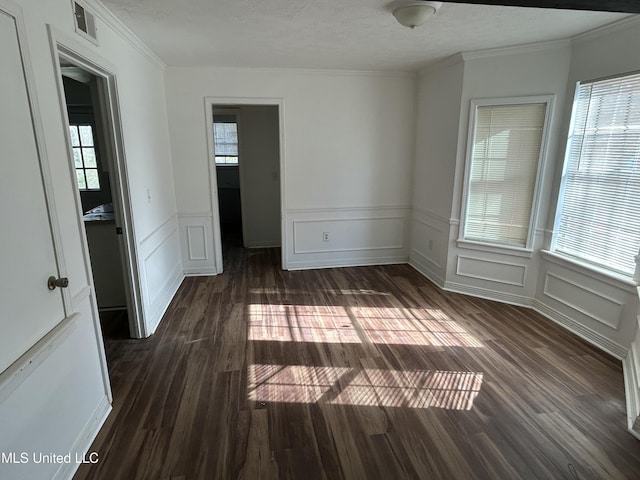 spare room with crown molding, dark wood-style flooring, and a textured ceiling