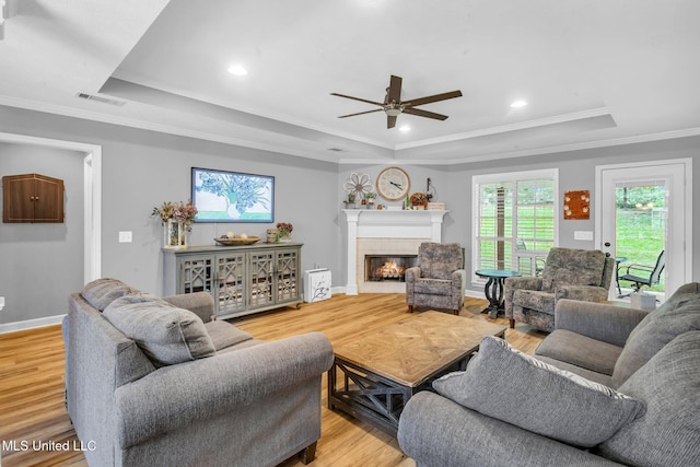 3007 Cross Point Cv, Brandon, MS 39042 - living room featuring a raised ceiling, ceiling fan, light wood-style flooring, a glass covered fireplace, and crown molding