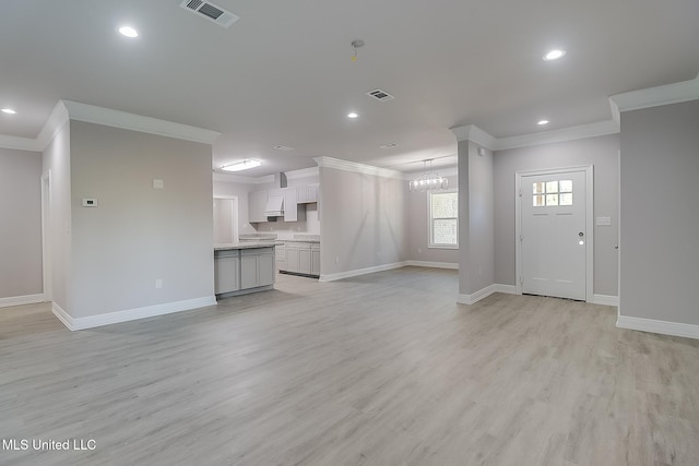 unfurnished living room with light hardwood / wood-style flooring, an inviting chandelier, and ornamental molding