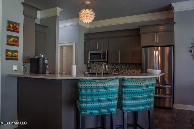 414 Spike Rdg, Canton, MS 39046 - kitchen featuring stainless steel appliances, decorative backsplash, crown molding, a breakfast bar area, and dark tile patterned floors