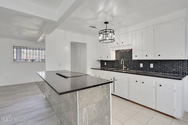 kitchen with pendant lighting, beam ceiling, sink, and white cabinets