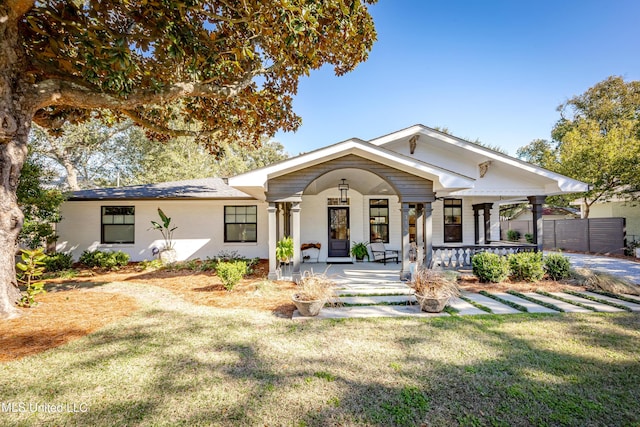 view of front of property with covered porch, a front lawn, and fence