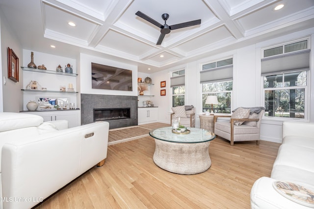 living room with a glass covered fireplace, coffered ceiling, and light wood-style flooring