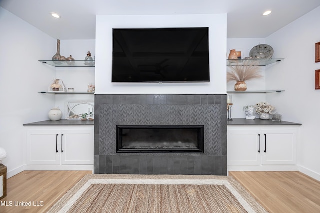 interior space with recessed lighting, a fireplace, baseboards, and wood finished floors