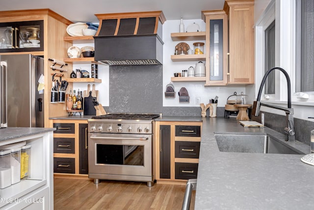 kitchen featuring glass insert cabinets, high quality appliances, custom exhaust hood, and a sink