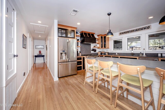 kitchen with stainless steel appliances, hanging light fixtures, dark countertops, and visible vents