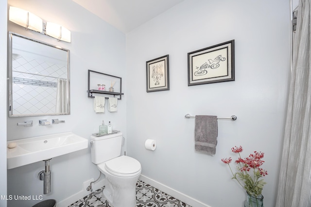 bathroom with a shower with shower curtain, baseboards, and toilet