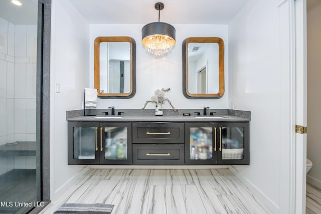 full bath with double vanity, baseboards, a chandelier, and a sink