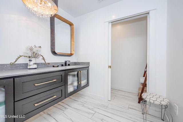 bathroom featuring baseboards, a notable chandelier, and vanity